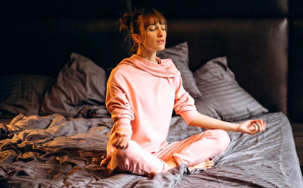 Jeune femme médite sur son lit