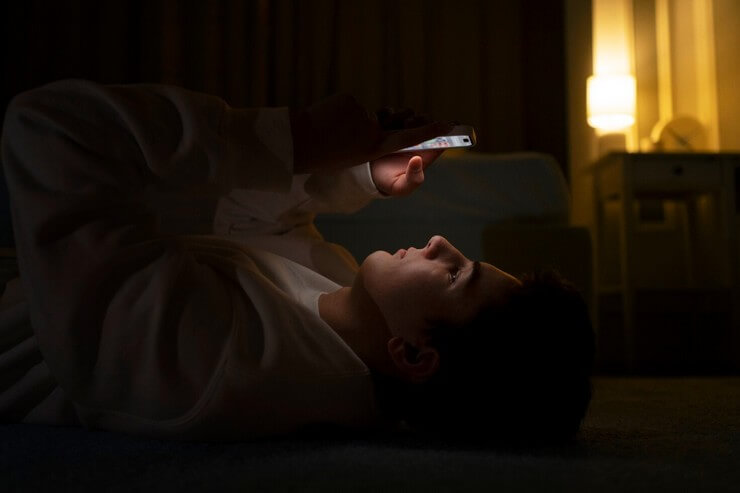 Jeune homme devant son téléphone au lit